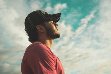Man taking a deep breath outdoors with clear sky in background