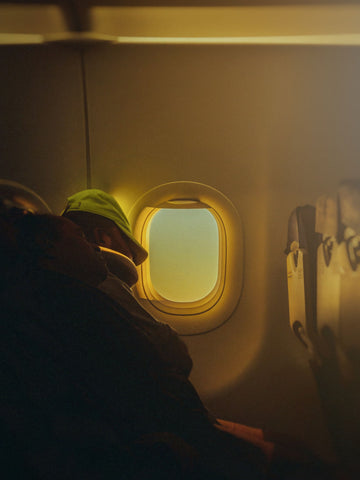 Passengers sleeping in their seats inside a dimly lit airplane cabin on a long flight
