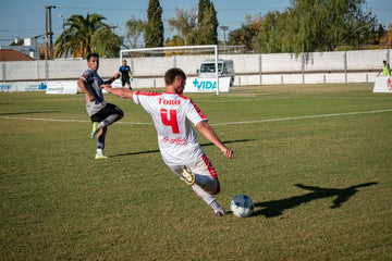 Two footballers competing for the ball during a match on a grass pitch