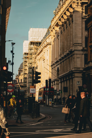 Red double decker bus and shoppers on a London street near an Underground station sign, United Kingdom