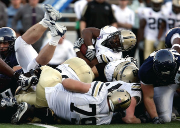 American football players in full pads clashing during a tackle on the field
