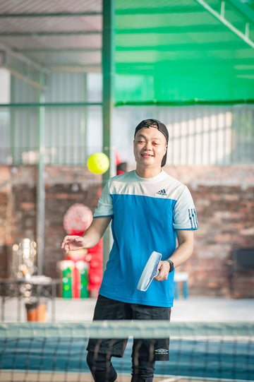 Table tennis player mid rally reaching to return a shot indoors