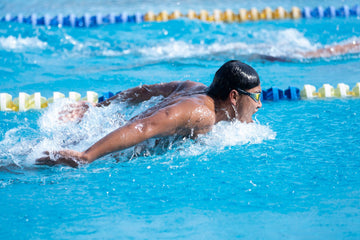 Competitive swimmer mid stroke in a pool lane during a race, water splashing around them