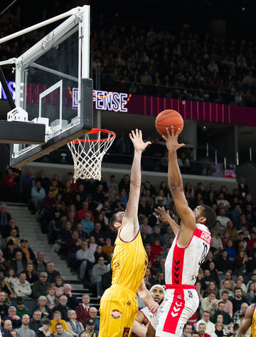 Basketball player driving to the hoop for a dunk during an intense indoor game