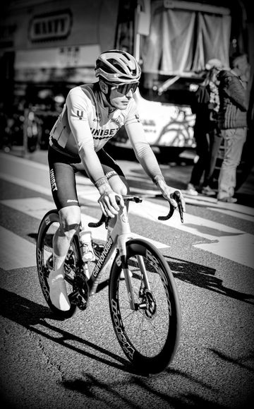 Professional cyclist on a road race wearing a helmet, breathing hard during intense effort