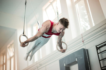 Male gymnast holding a strength position on the rings mid routine