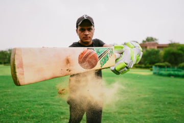 Cricket batsman playing an attacking shot with dust rising from the pitch