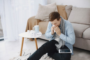 Man with a blocked nose and a cold wiping his nose with a tissue at home