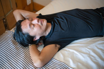 Man asleep on his back in bed with his eyes closed, breathing through his nose at night