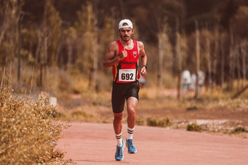 Man running on a dirt road outdoors, wearing a tank top